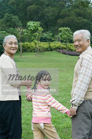 Girl walking hand in hand with grandparents