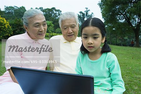 Girl and grandparents using laptop