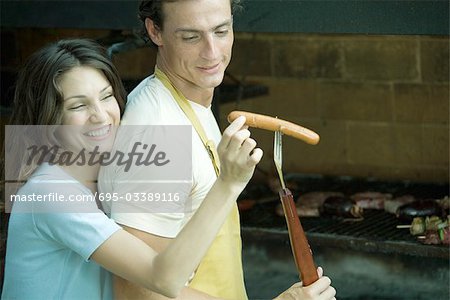 Couple having cookout, woman taking hotdog from man's fork