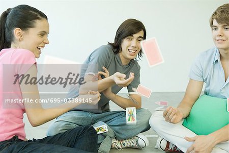 Teenage friends throwing playing cards into the air