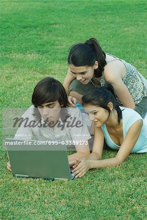 Gruppe junger Freunde liegend im Gras mit laptop