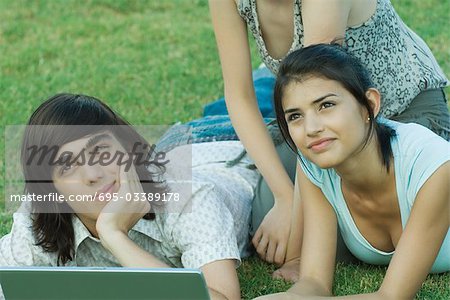 Gruppe junger Freunde lying on Grass mit laptop