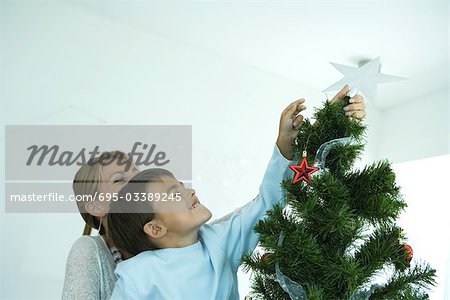 Knaben und Mutter schmücken Weihnachtsbaum