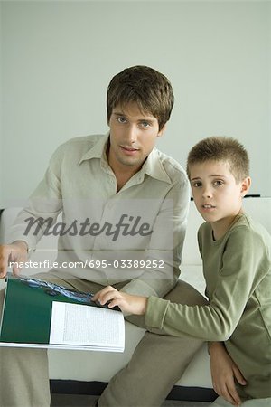 Father and son looking up from magazine