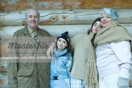 Grandparents and granddaughters standing by chalet, portrait