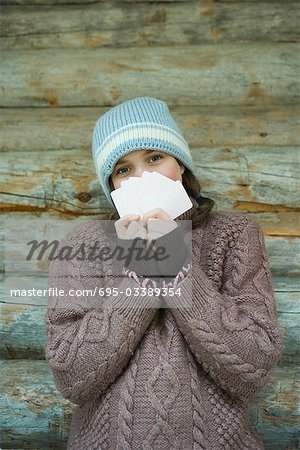 Teenage girl looking over cards, dressed in winter clothing, portrait