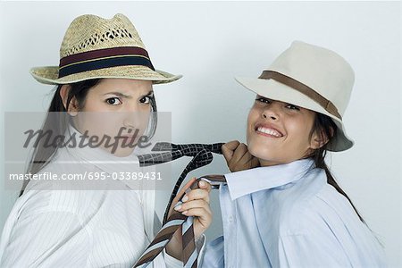 Zwei junge Freundinnen in Button down Hemden, Krawatten und Hüte gekleidet, ziehen auf jeder des anderen Riegeln, Porträt