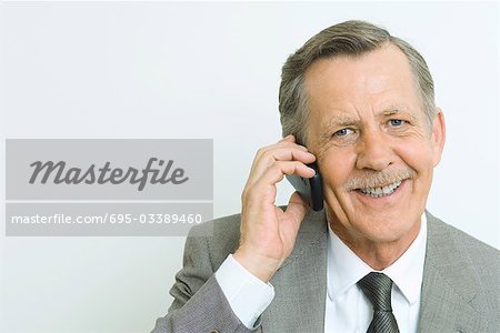 Entrepreneur principal à l'aide d'un téléphone cellulaire, souriant à la caméra, portrait