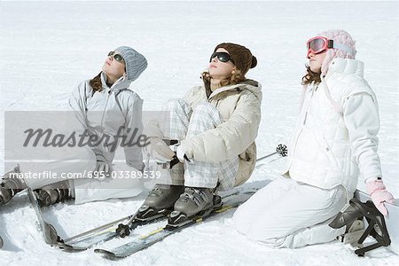Trois skieurs adolescente assis dans la neige, lunettes de soleil, têtes arrière