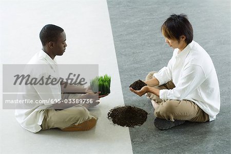 Zwei Männer sitzen Angesicht zu Angesicht, ein Betrieb aus Gras, die holding aus Boden, Seitenansicht