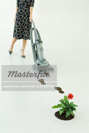Woman vacuuming up footprints of soil, low section
