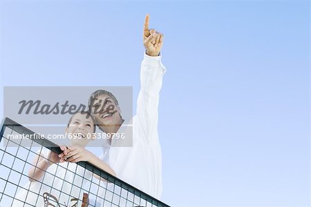 Homme debout à l'extérieur avec la fille, pointant vers le haut dans le ciel, les deux à la recherche et souriant, faible angle vue