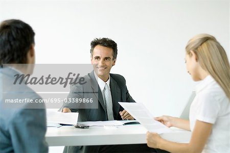 Businessman discussing contract with couple, smiling