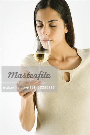 Woman smelling glass of white wine, eyes closed