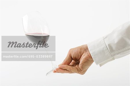 Hand tipping glass of red wine