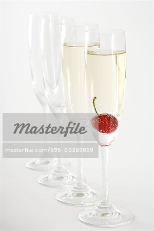 Champagne flutes, two filled with champagne, one with a cherry floating in it Champagne flutes, two filled with champagne, one with a cherry floating in it