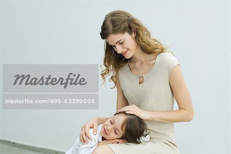 Petit garçon se reposer la tête sur les genoux de sa mère, femme caresser les cheveux de l'enfant