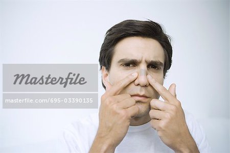Man applying adhesive bandage on his nose, looking at camera