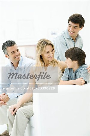 Family together on sofa, mother's arm around younger son's shoulder