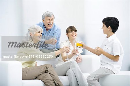 Multi-generation family clinking glasses, smiling at each other