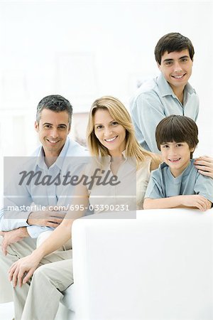 Family sitting together on sofa, smiling, portrait