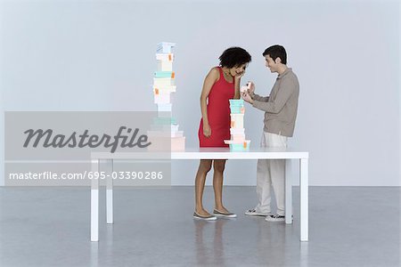 Couple standing beside table stacked with boxes, man giving woman a gift