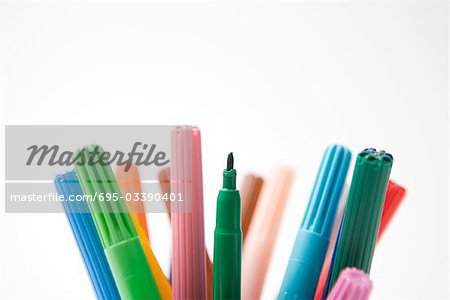 Tops of multicolored felt tip pens, one missing its cap, close-up