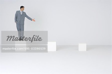 Businessman standing on pedestal, presenting empty pedestals