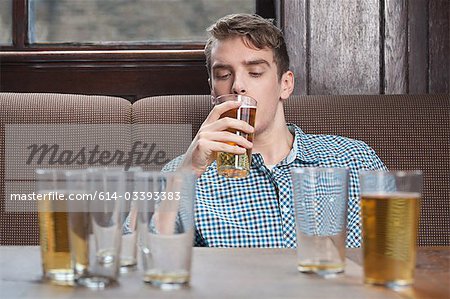 Young man drinking beer in bar