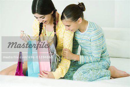 Two young female friends, one opening up gift bags
