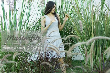 Woman standing in ornamental garden, looking at foliage