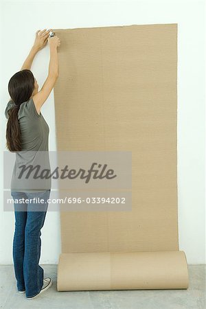 Femme agrafage carton ondulé sur le mur
