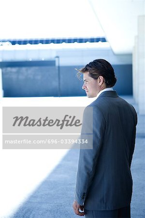 Young businessman standing, looking away, three quarter length