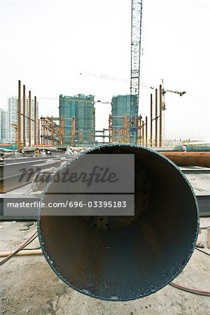 Construction site, end of metal pipe in foreground