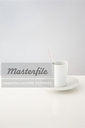 Cup resting on saucer, spoon in cup Cup resting on saucer, spoon in cup