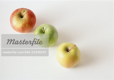Three apples, red, green, yellow, in diagonal line, against white background