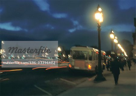 France, Paris, bus stopped next to sidewalk at night