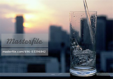 Glass with ice and straw in front of blurred cityscape