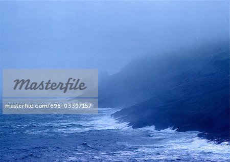 Wellen schlagen Küste im Nebel