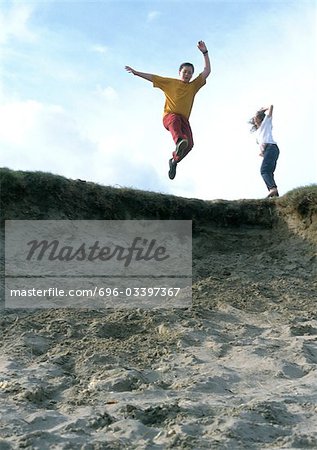 Young people jumping in sand