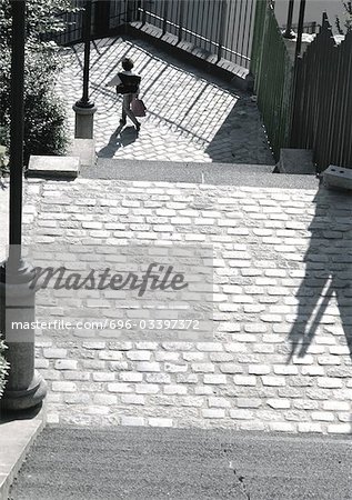 Person walking on cobblestone street, view from above.