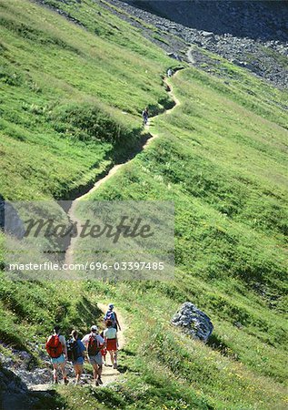 France, Savoie, hikers walking on footpath through green hillside