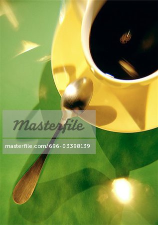 Café en tasse jaune et une soucoupe avec cuillère sur fond vert