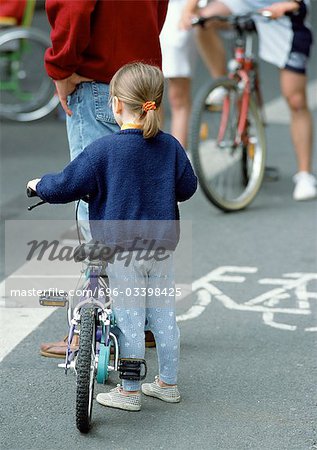 Kleine Mädchen stehen neben Fahrrad in Bikelane, Rückansicht