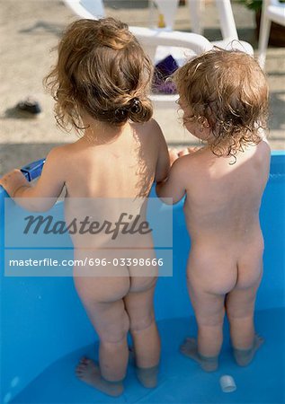 Two children standing in water, rear view