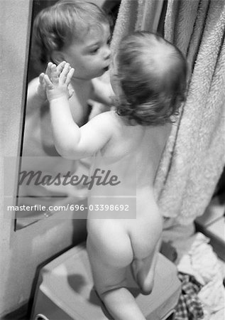 Toddler leaning against mirror, b&w