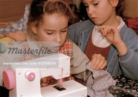 Two girls side by side, one using sewing machine