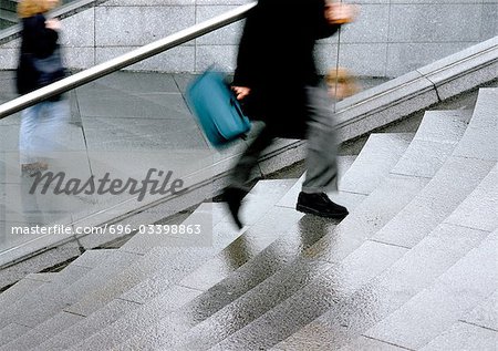 Man rushing up stairs, low section, blurred motion