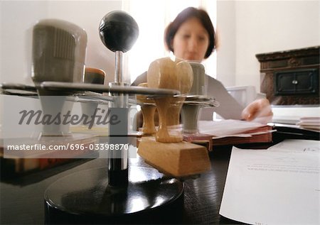 Stampers on rack, and woman sitting at desk, blurred