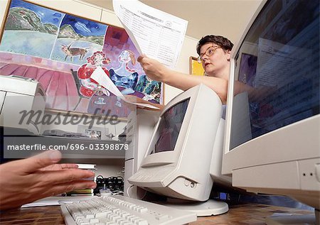 Woman leaning on computer screen, holding documents, low angle view